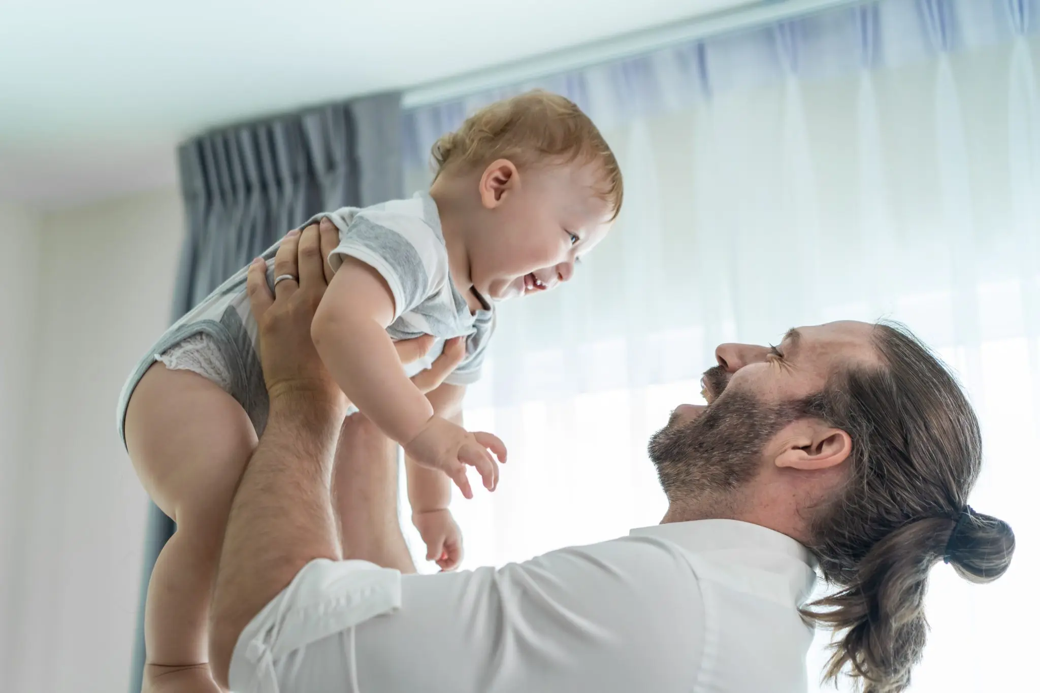 papa tenant son bébé dont le regard a l'air de dire je t'aime papa