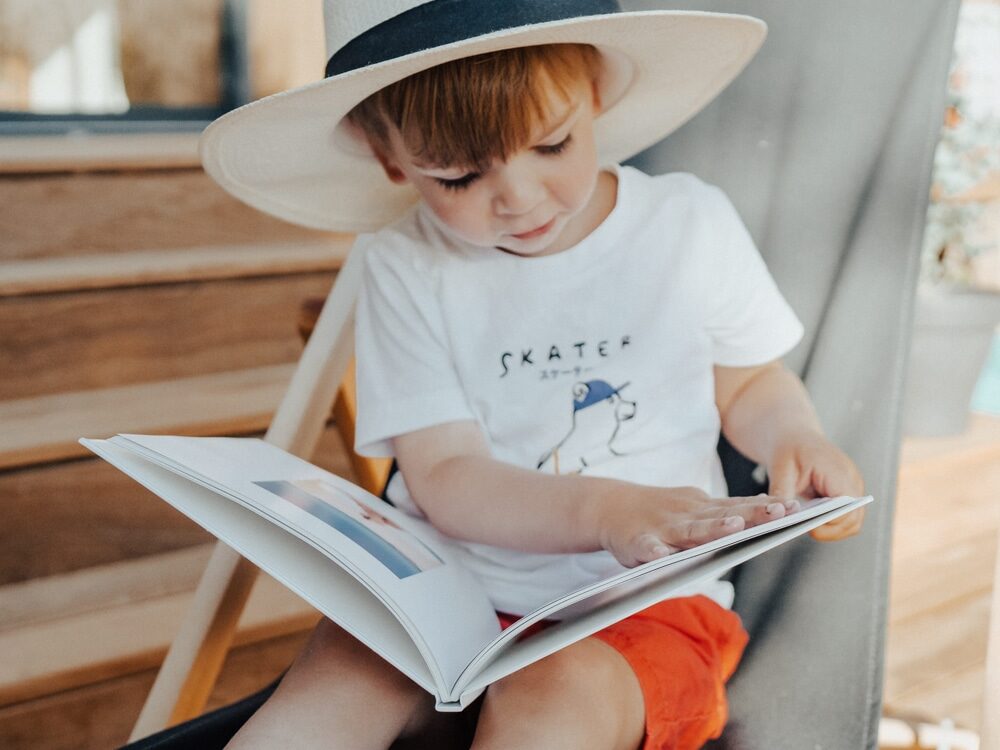 child with hat reading a photo book